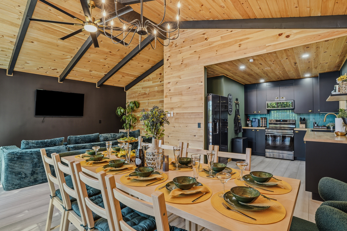 Designer dining area with vaulted wood ceiling, statement lighting, and open flow to the kitchen