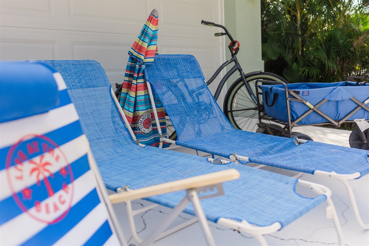 Multiple styles of lounge chairs, an umbrella, 2 adult bikes, beach wagon, and a cooler