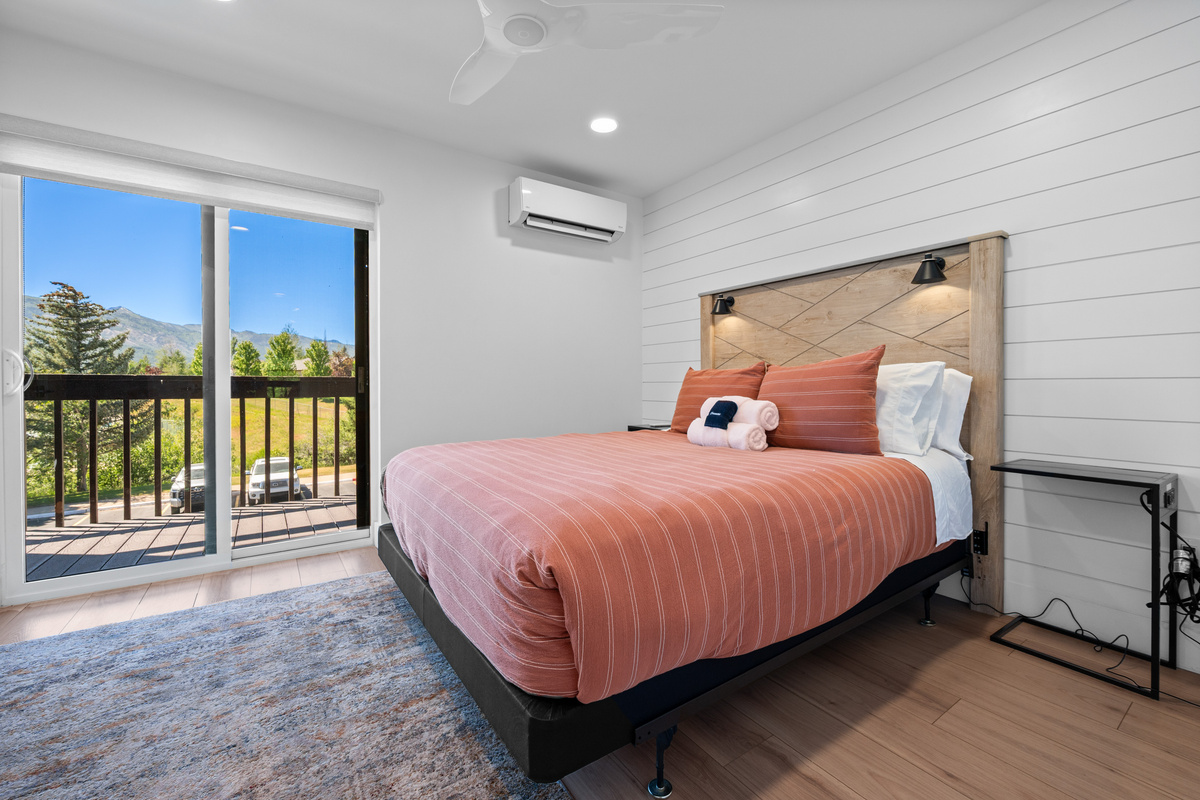 Main-level bedroom featuring a comfortable Queen bed and private balcony access.