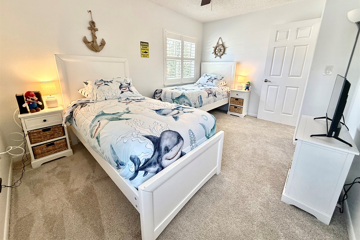 Fun and family-friendly room with two twin beds and playful shark-themed bedding.