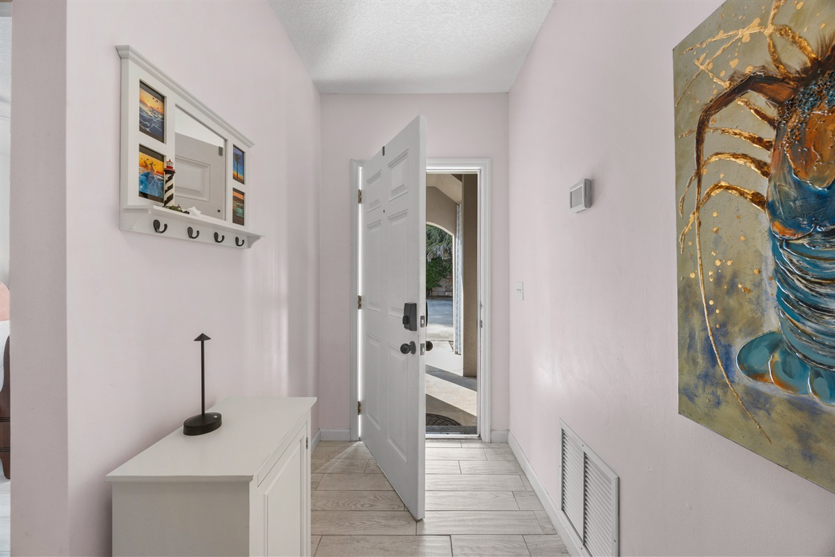 Bright and stylish entry hallway featuring coastal artwork, functional storage, and warm natural light.
