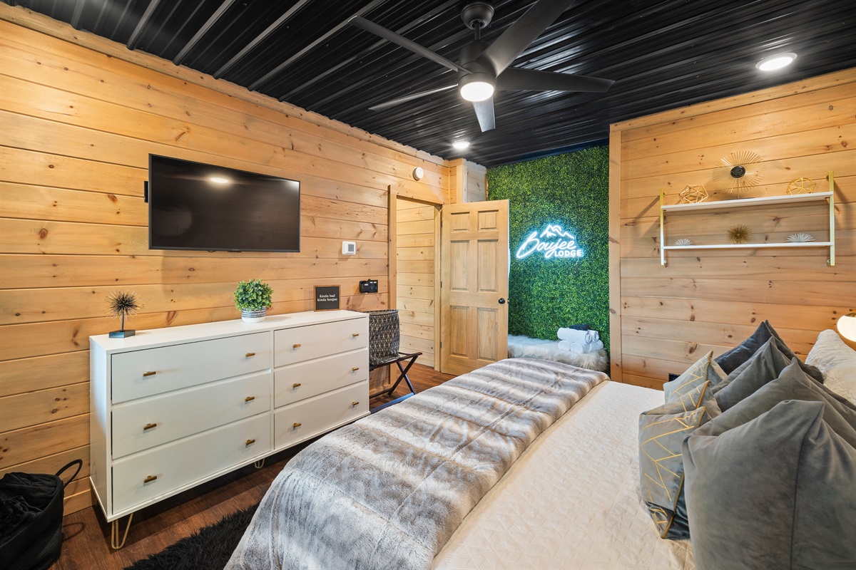 This contemporary king bedroom features cozy decor, soft lighting, and a greenery wall that adds that Boujee touch