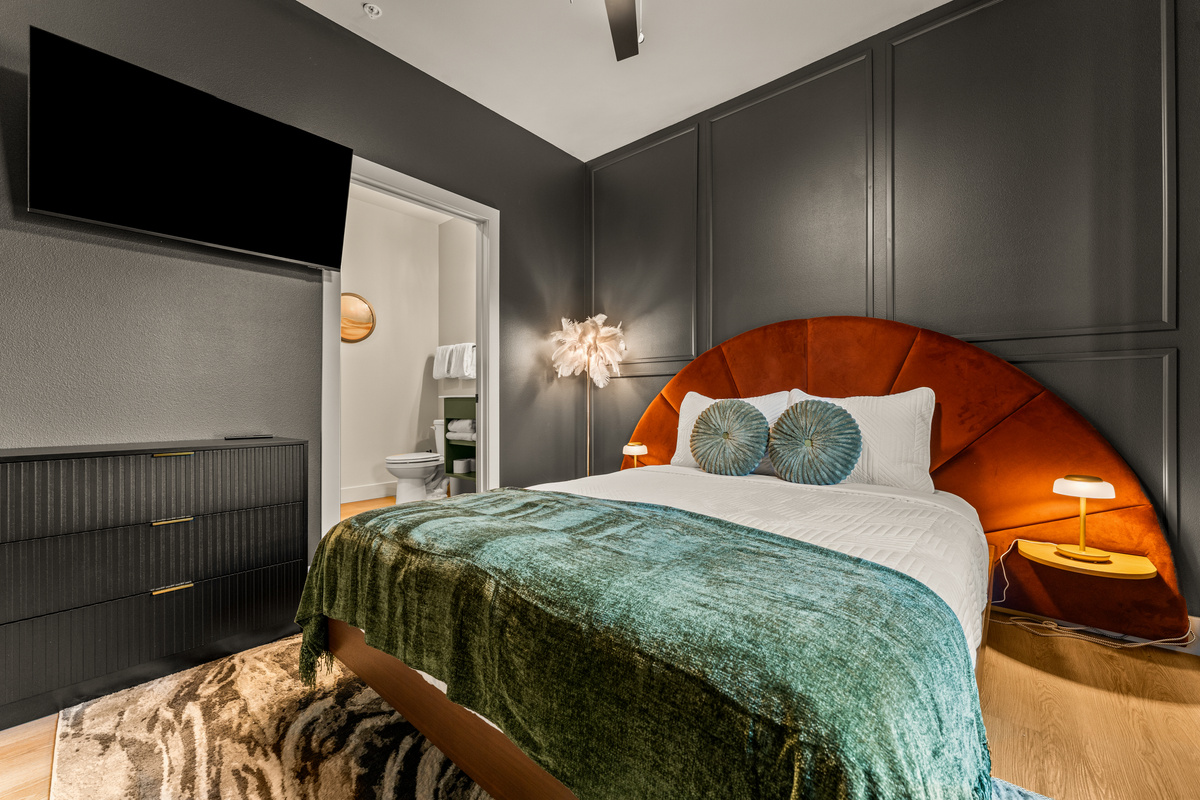 Rich green bedding, a dramatic upholstered headboard, and warm bedside lighting give this king bedroom a cozy, sophisticated feel.