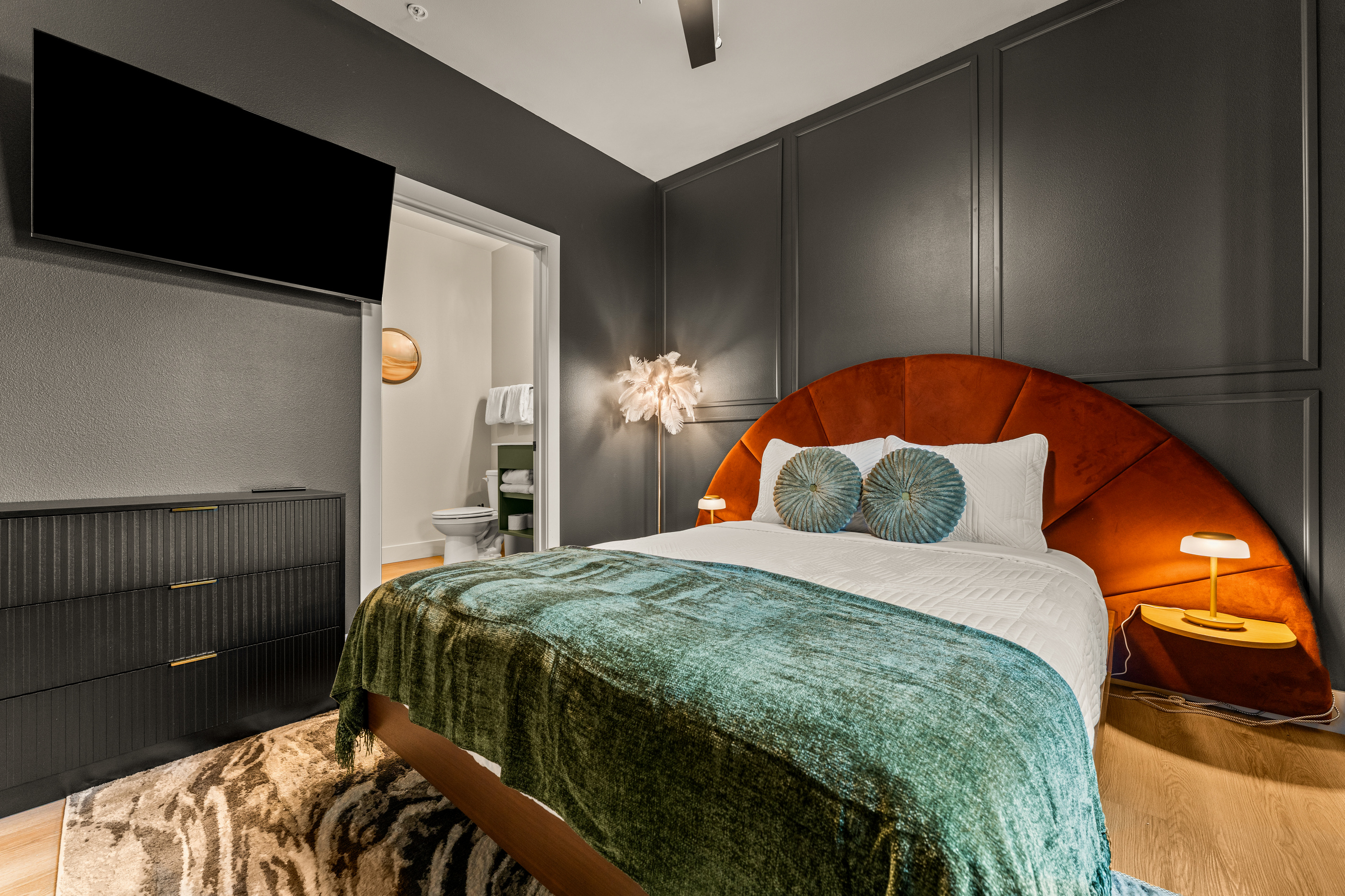 Rich green bedding, a dramatic upholstered headboard, and warm bedside lighting give this king bedroom a cozy, sophisticated feel.