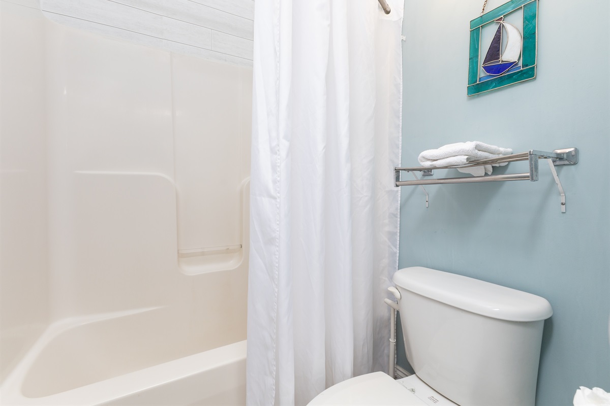 A clean and well kept bathroom featuring a tub/shower combo