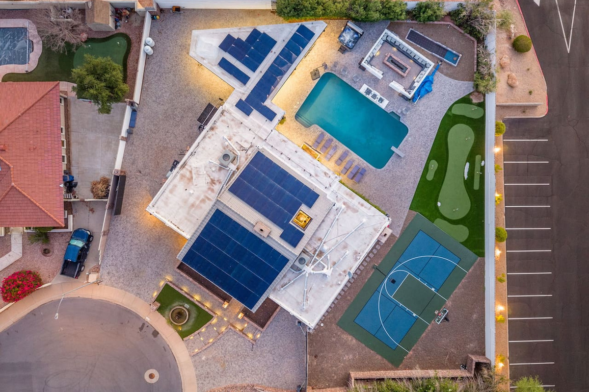 Straight-down drone view captures the pool, sport court, and solar-equipped roof — the full layout at a glance.