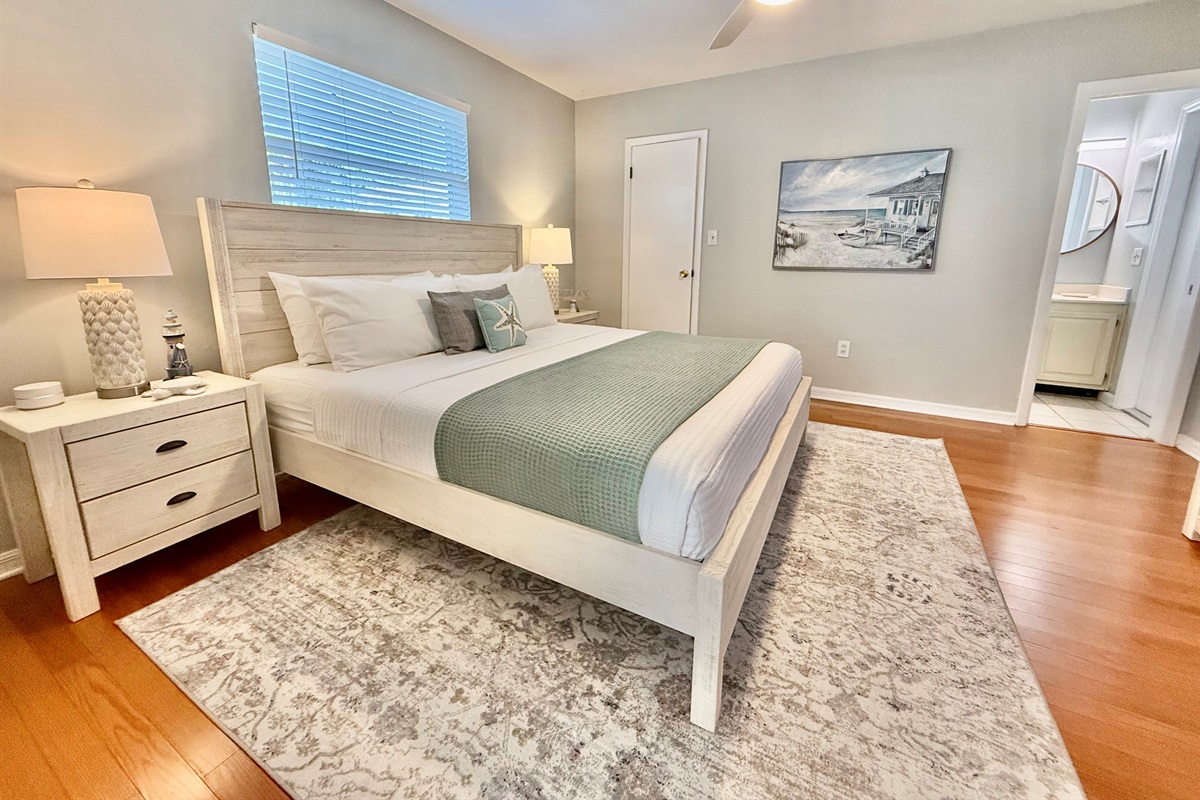 Sleep like royalty in this spacious master bedroom with hardwood floors, warm lighting, and a cozy ambiance.