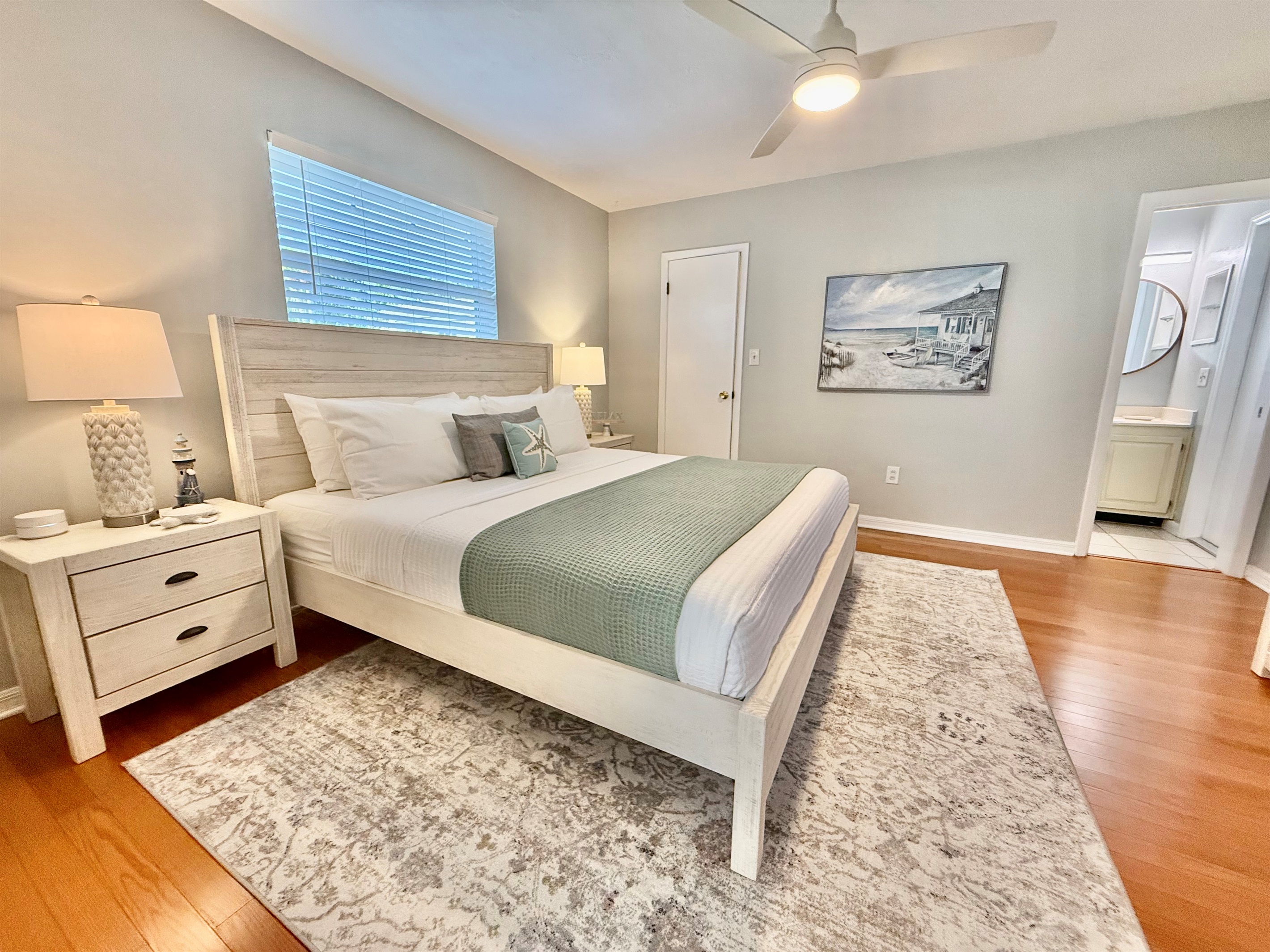 Sleep like royalty in this spacious master bedroom with hardwood floors, warm lighting, and a cozy ambiance.