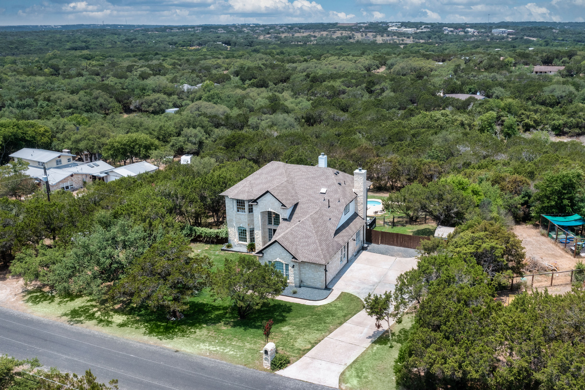 Panoramic aerial view highlighting the home's peaceful, wooded setting.