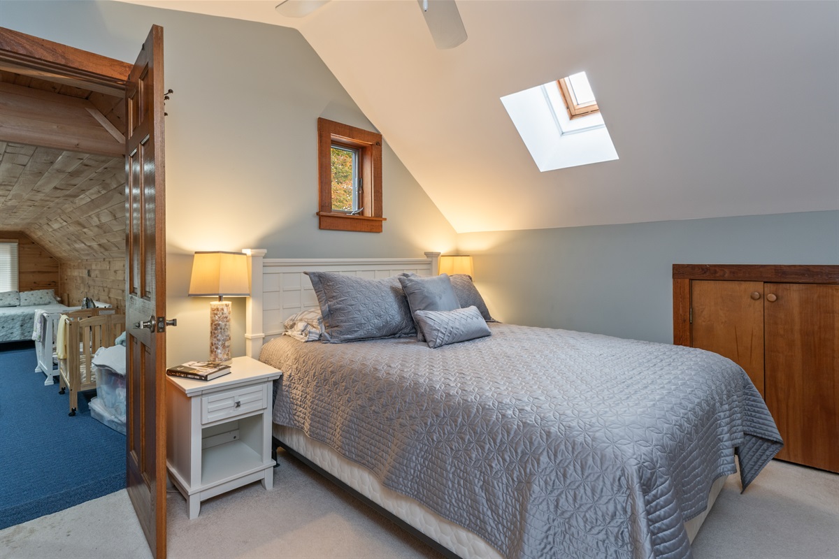 Elegant upper-level bedroom with warm lighting and vaulted ceilings — cozy and full of mountain-home charm.