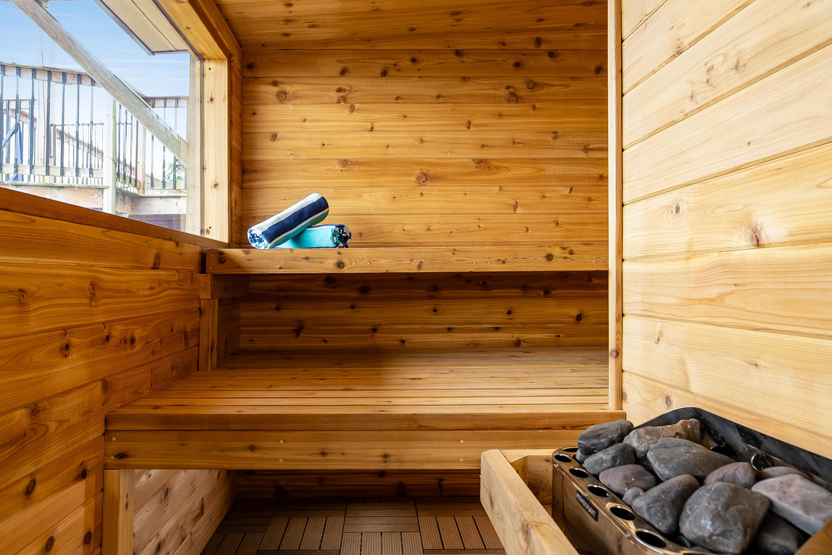 Inviting cedar sauna with spacious wooden benches and a stone-filled heater.