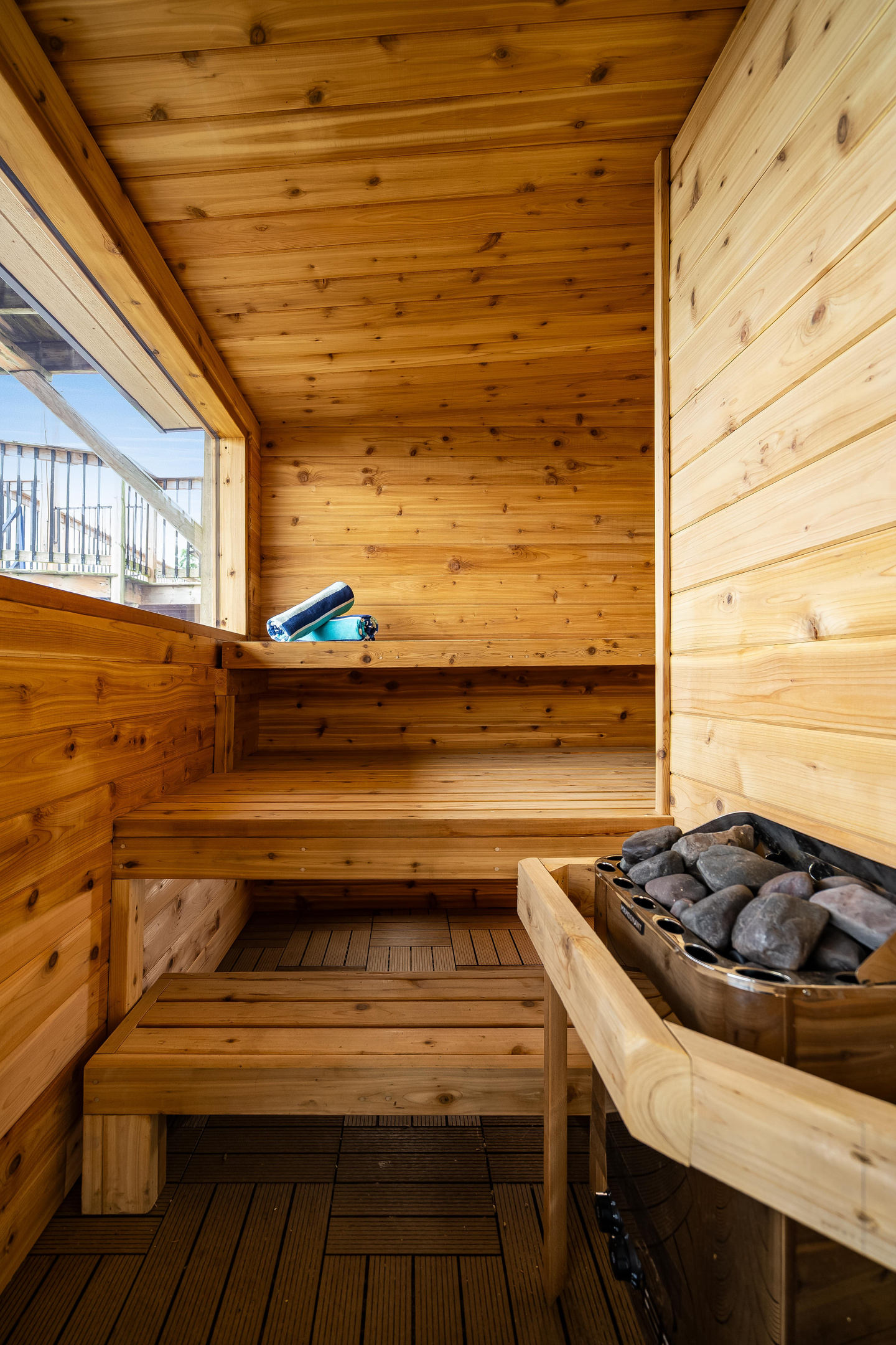 Inviting cedar sauna with spacious wooden benches and a stone-filled heater.