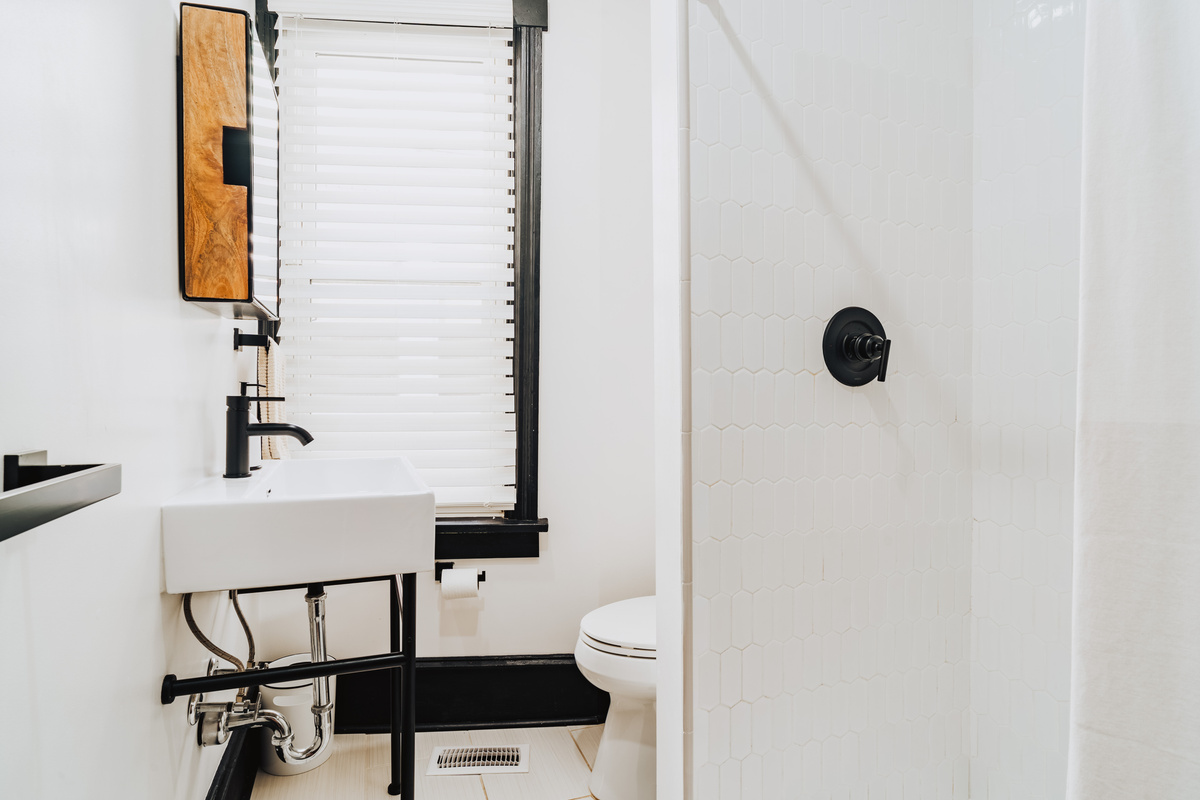 Bathroom View Showing White Pedestal Basin, Mirror Cabinet, and Tiled Shower Wall