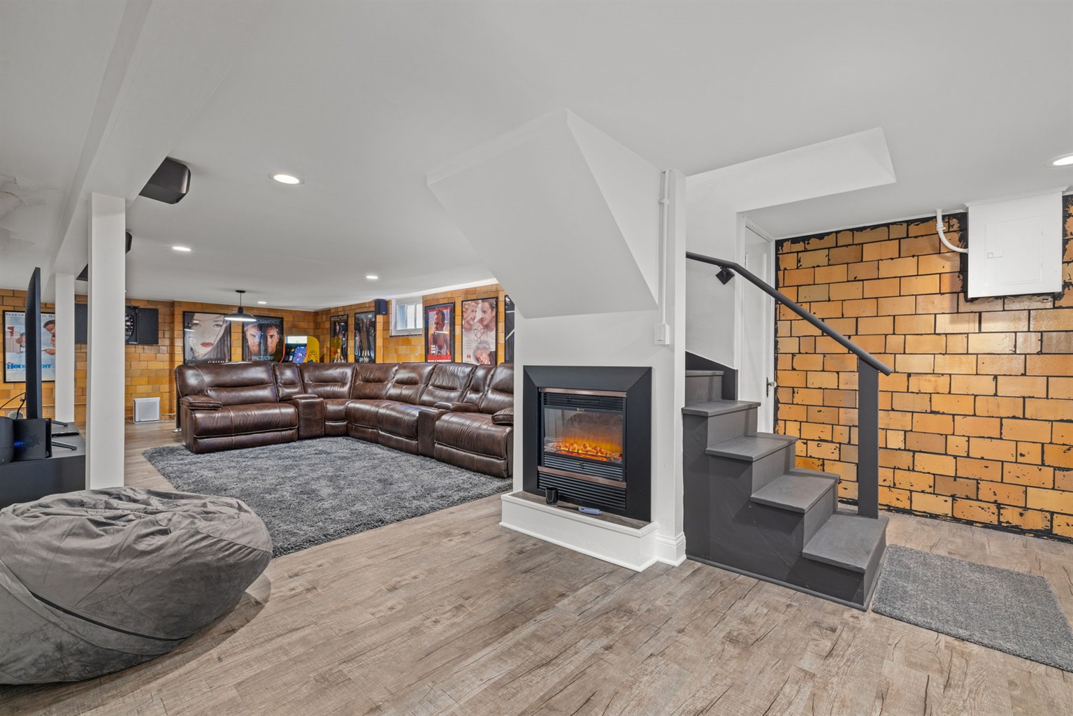 Lower level entertainment room with artificial fireplace, large sectional with 3 power recliners,   75" flatscreen smart TV with surround sound, dry bar, foosball table, air hockey/pool table,