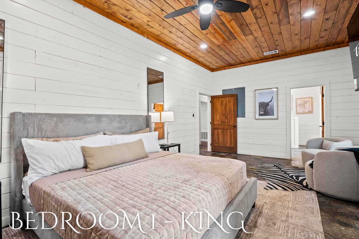 A peaceful king suite with warm wood tones, plush bedding, and a cozy seating area for unwinding in comfort.