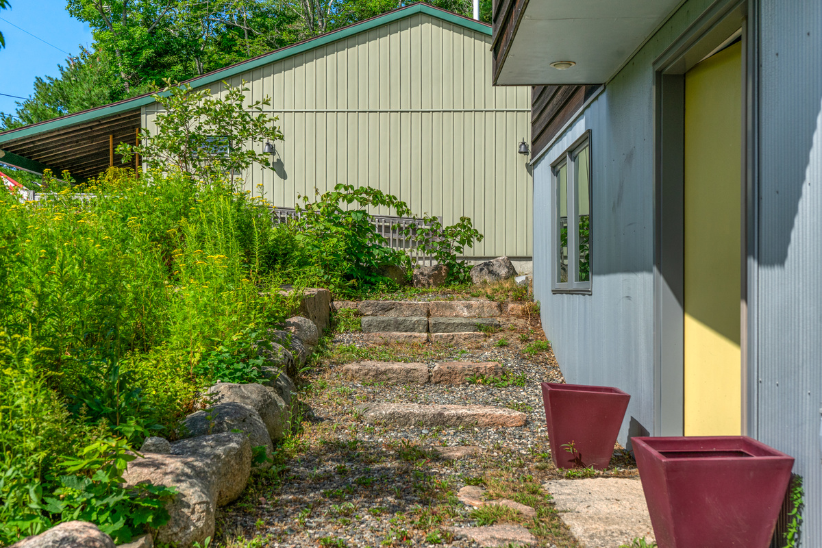 The Base Camp entry at "The Crag," featuring granite steps leading around to the rear grounds. A separate step-free path provides easier access directly to the main floor for guests seeking a smooth, gradual walk.