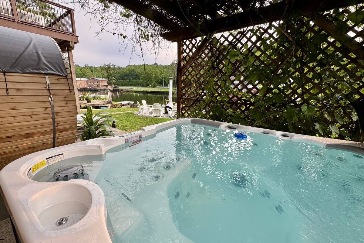 River Spa Patio — Soak in the hot tub while overlooking the river, cedar sauna, and waterfront fire pit.