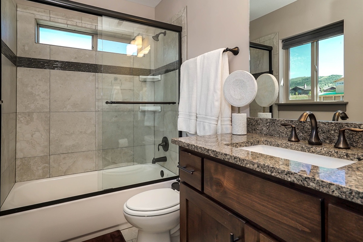 Clean and modern ensuite bathroom with tub/shower combo for bedroom 1.