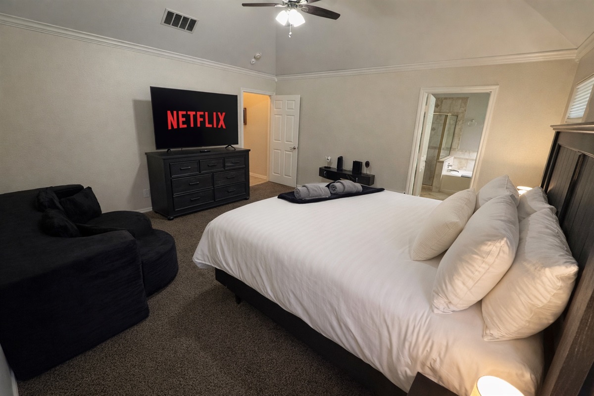 Open and airy bedroom with plush carpet, elegant furnishings, king bed, and a full sleeper sofa for flexible sleeping arrangements.