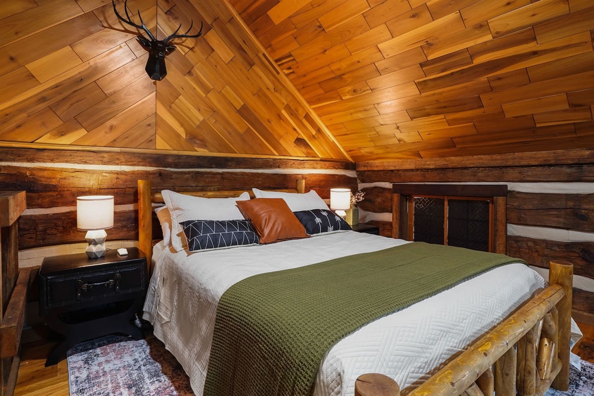 The bedroom features two rustic side tables, a rustic dresser, a cloth hanging rack, and a white noise machine.