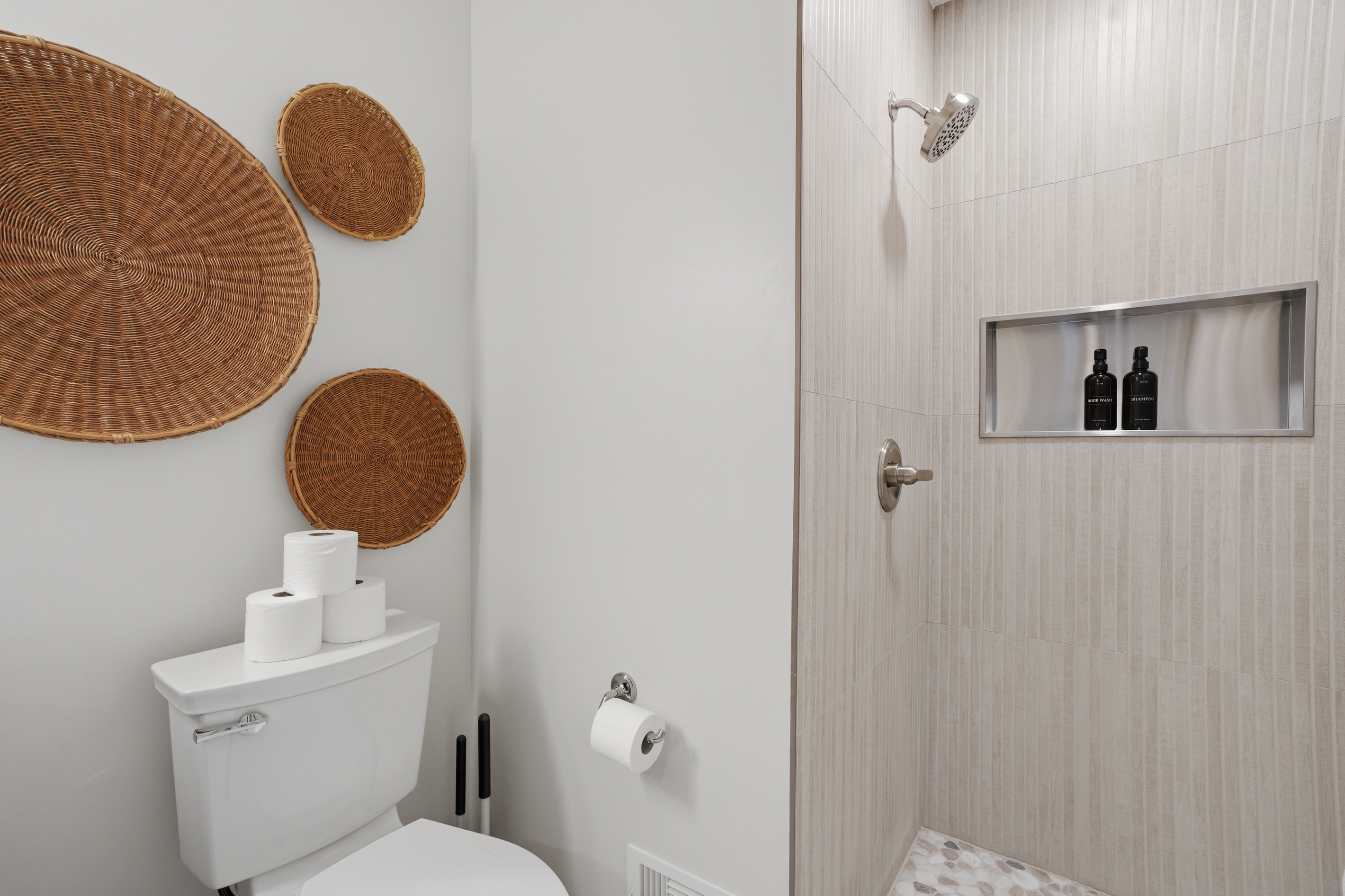 Modern bathroom with elegant stone tile walk-in shower, built-in niche, and warm woven accents. Clean, spa-inspired design with a bright, calming, hotel-like feel.