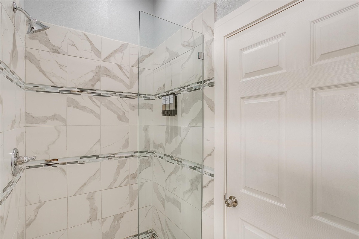 Walk-in tiled shower with glass accents and solid pressure.