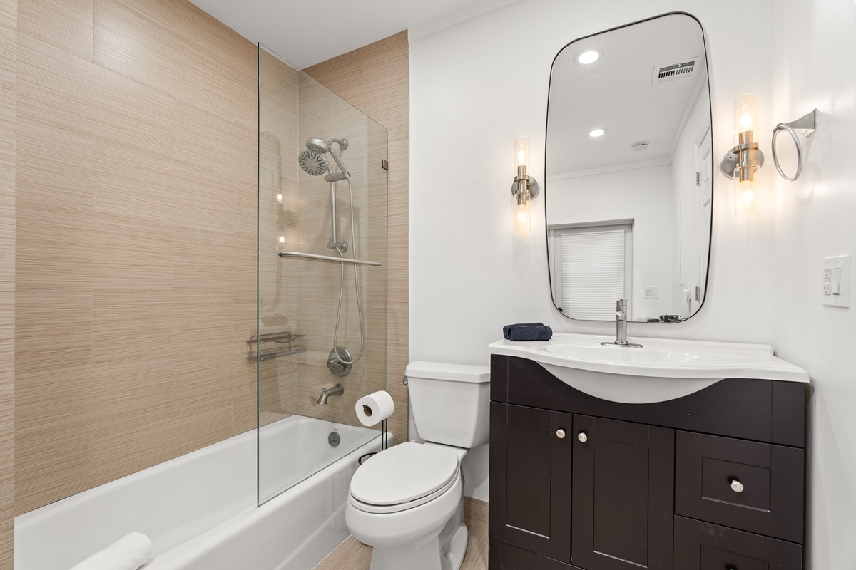 Modern full bathroom with a tub/shower combo, sleek vanity, and soft ambient lighting.