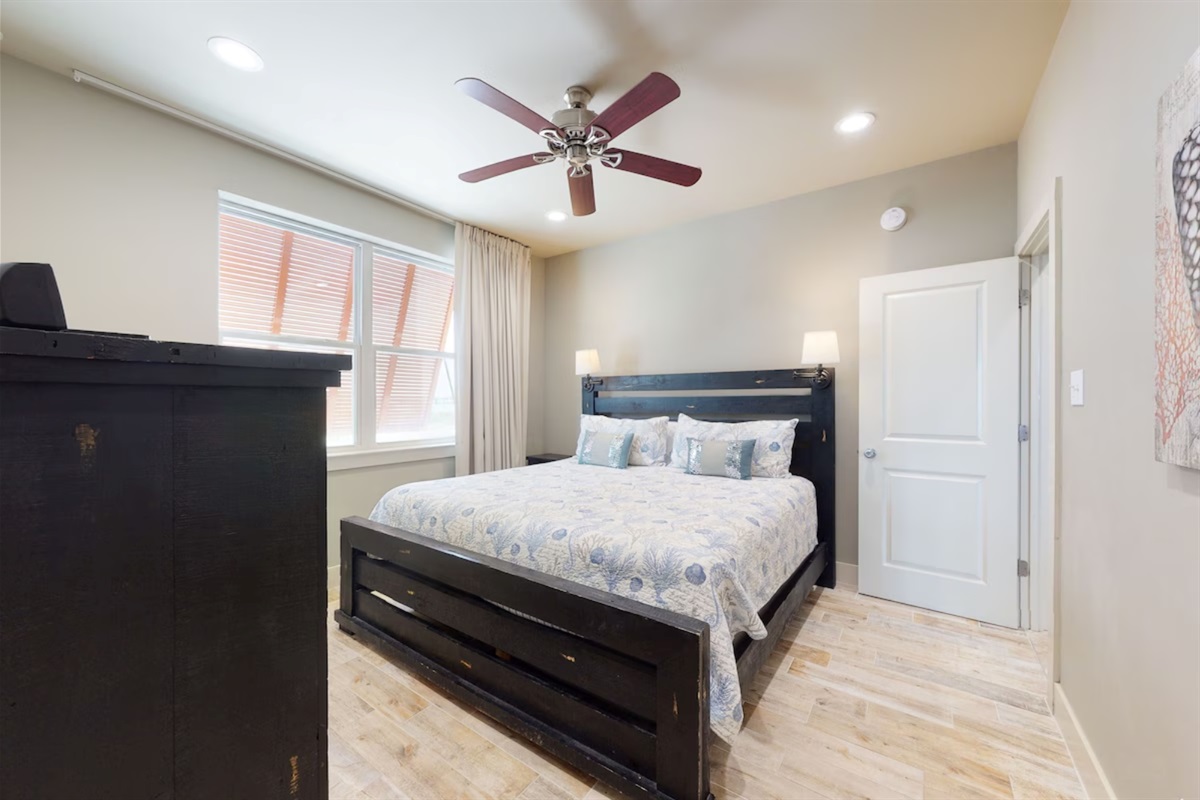 Main level bedroom with king bed, ceiling fan, TV and en-suite bathroom  