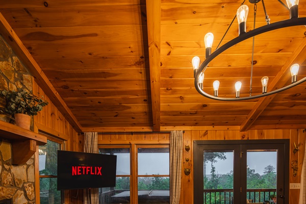 A warm, nostalgic living room wrapped in rich wood tones, with a Roku TV for easy entertainment inviting you to slow down, settle in, and feel at home in the mountains. 