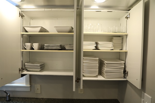 Kitchen cabinet showing plates, cups, and bowls