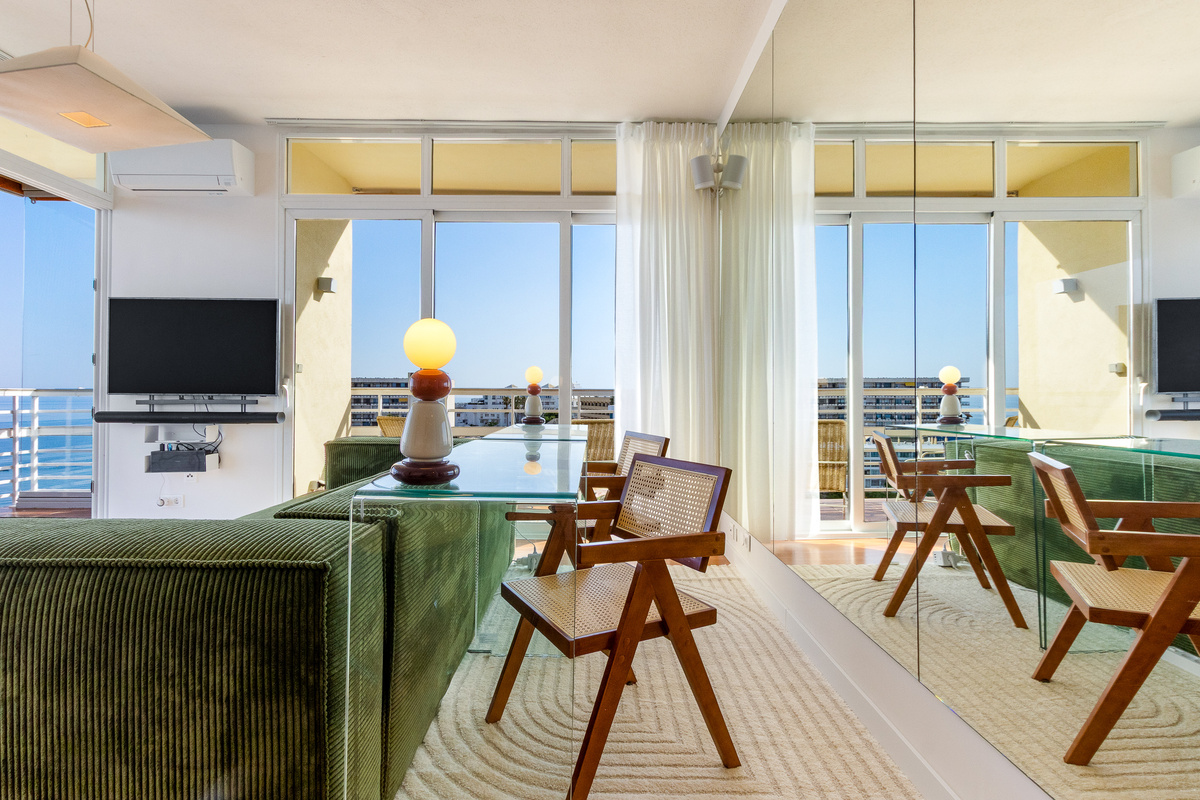 Design-led living room with mirror wall, lounge seating and sea-facing windows.