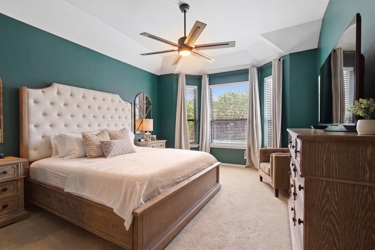 Master Bedroom featuring a King Bed, plush upholstered headboard, ceiling fan, and a 65-inch Smart TV. A restful retreat after a day exploring Toyota Stadium, Legacy West, or Grandscape.
