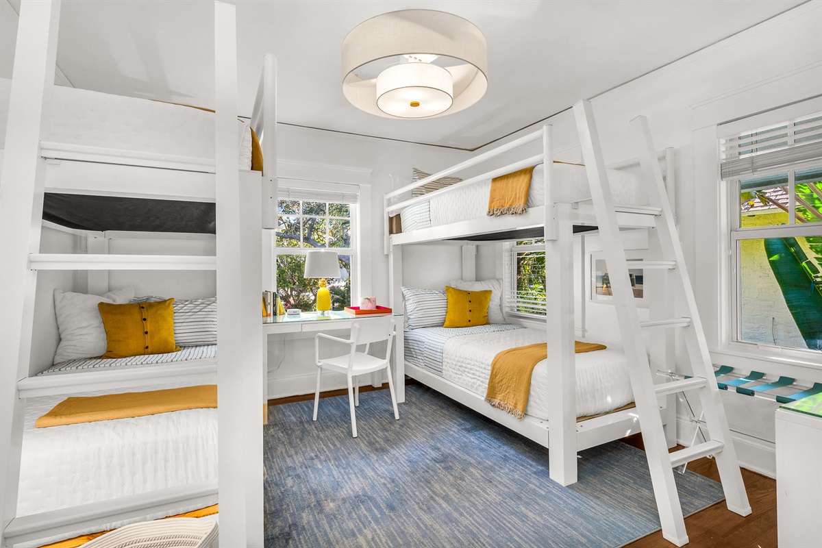 Bright and airy bunk bed bedroom featuring two new durable twin XL bunk beds, modern artwork, and a personal desk and chair—ideal for remote work. Enjoy a smart TV and peaceful views overlooking the quiet Flamingo Park street.