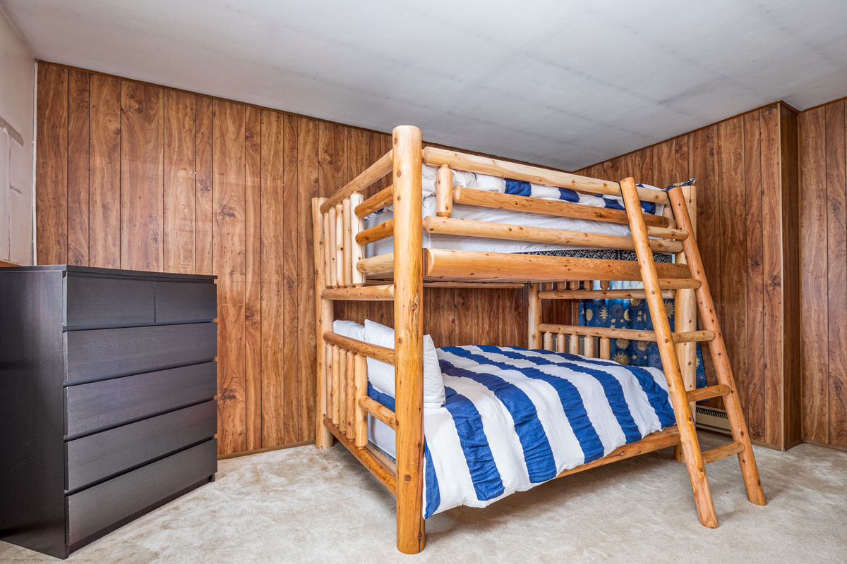 Bunk room with dresser and warm wood finishes