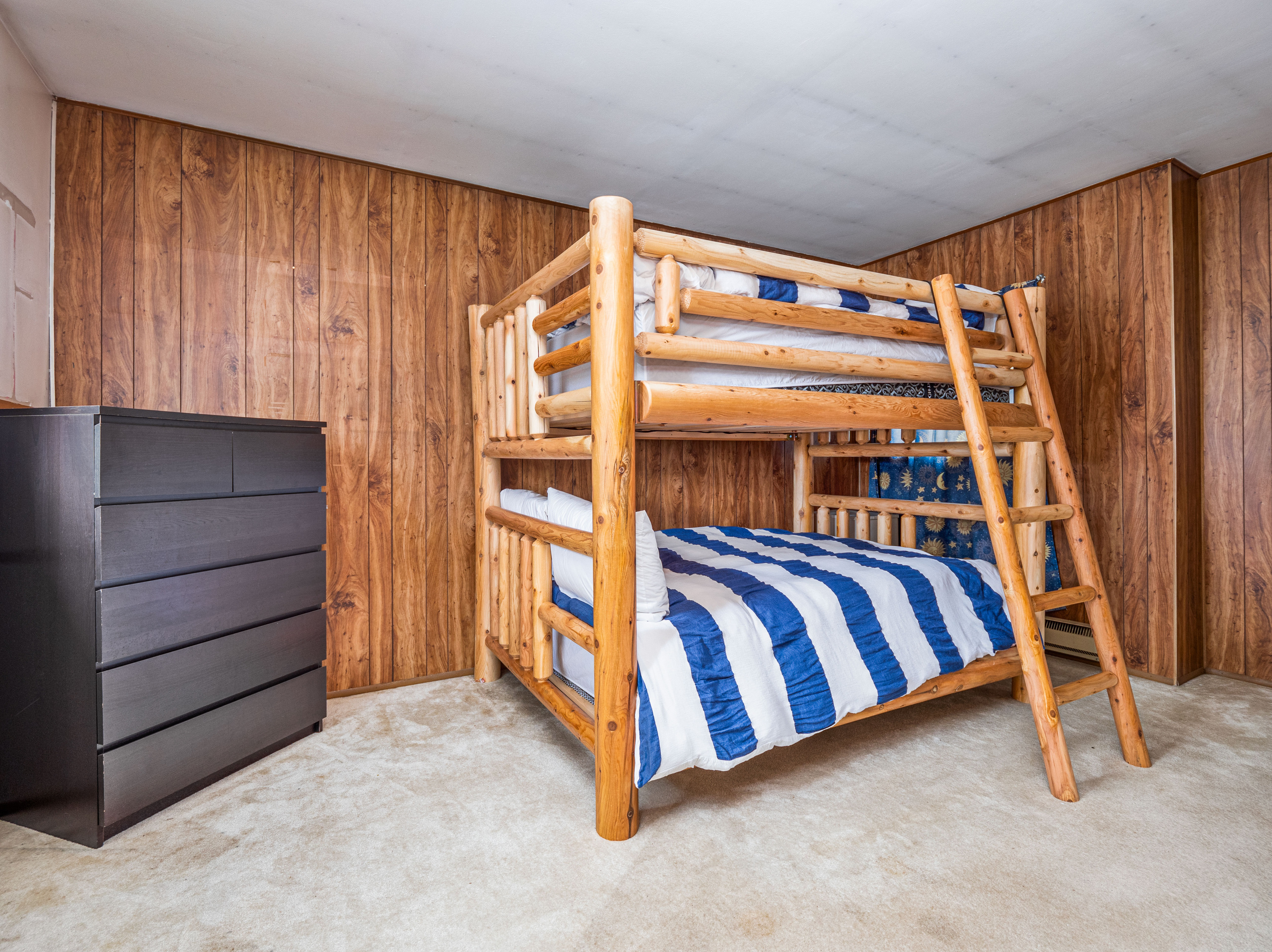 Bunk room with dresser and warm wood finishes