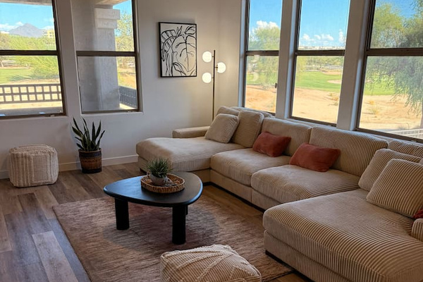 Living room with oversized sectional seating, wide windows, and open views of the desert landscaping outside.