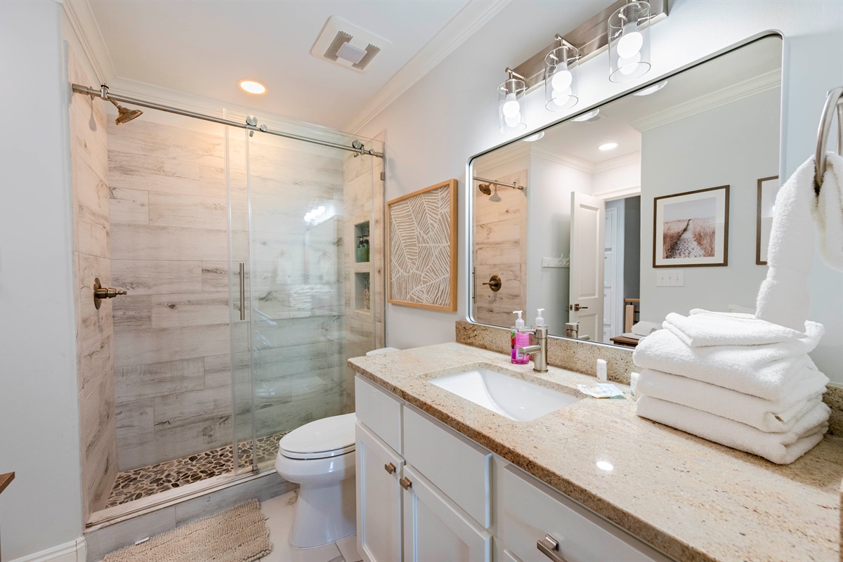 Stylish bathroom haven with a glass shower, sleek vanity, and cozy accents.