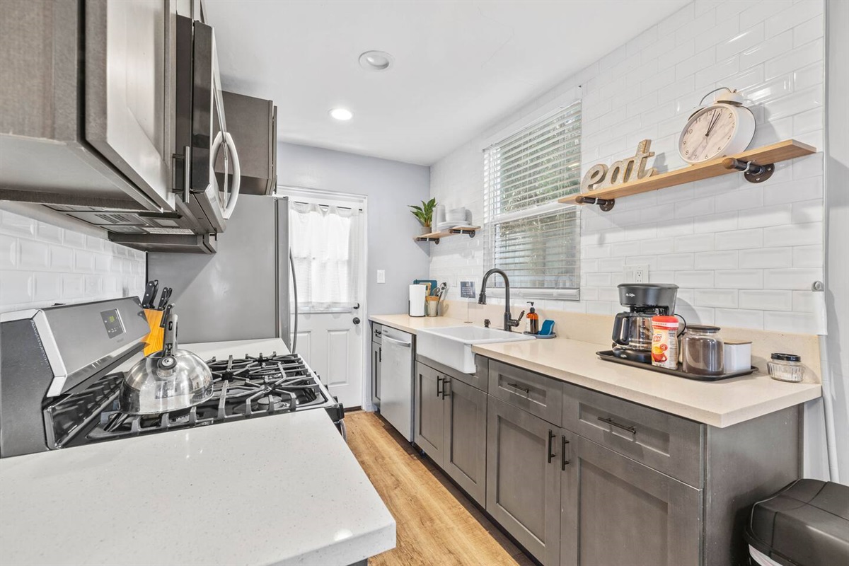 Our kitchen offers modern convenience with a sleek sink, efficient dishwasher, and coffee maker for your daily brew. A vibrant plant adds a refreshing touch, creating a bright and welcoming space for cooking and relaxation during your stay!
