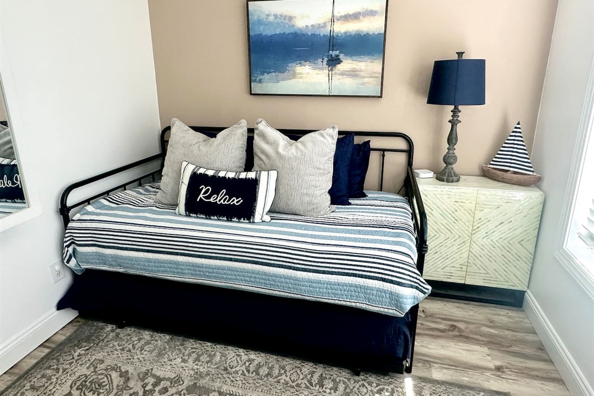 Unwind in this charming coastal-themed nook featuring a versatile daybed with a pull-out trundle. Perfect for extra guests or a quiet afternoon nap, the space is complete with nautical decor and a "Relax" pillow to set the vacation mood.