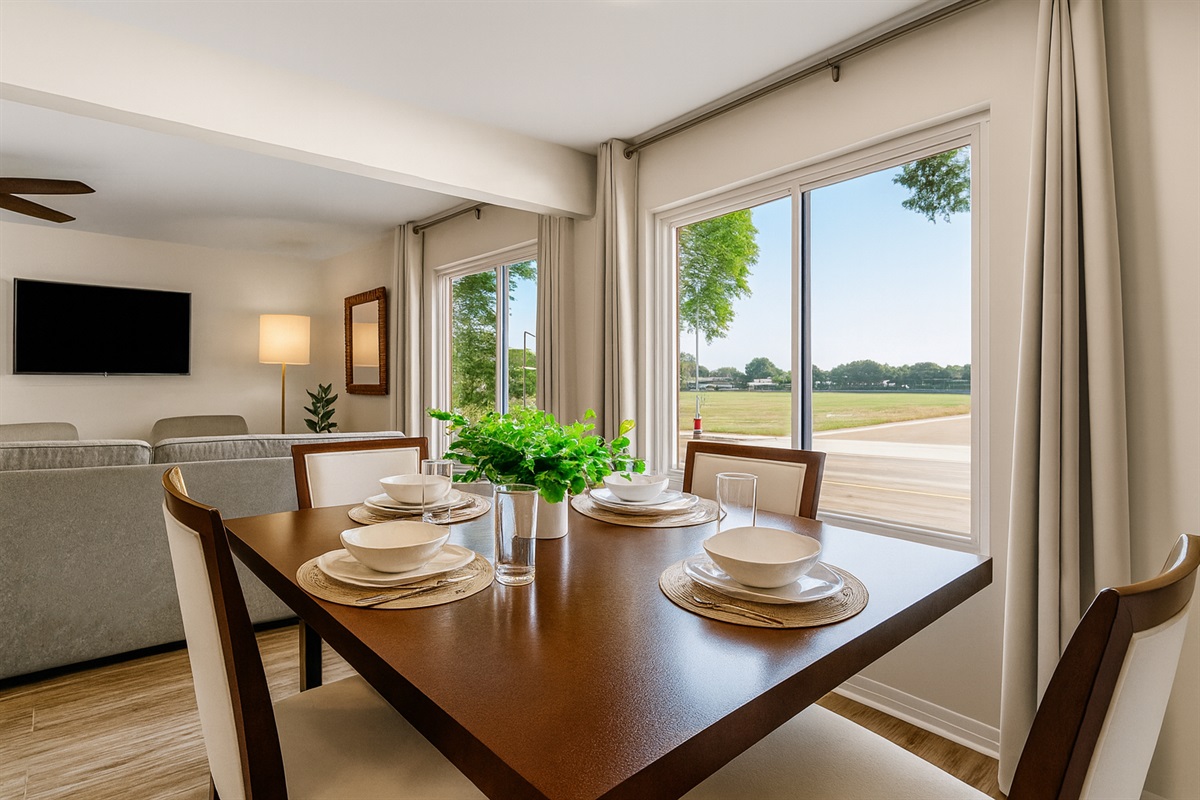Bright dining area with large windows, natural light, and a stylish table setup overlooking the living room—perfect for meals with a view.
