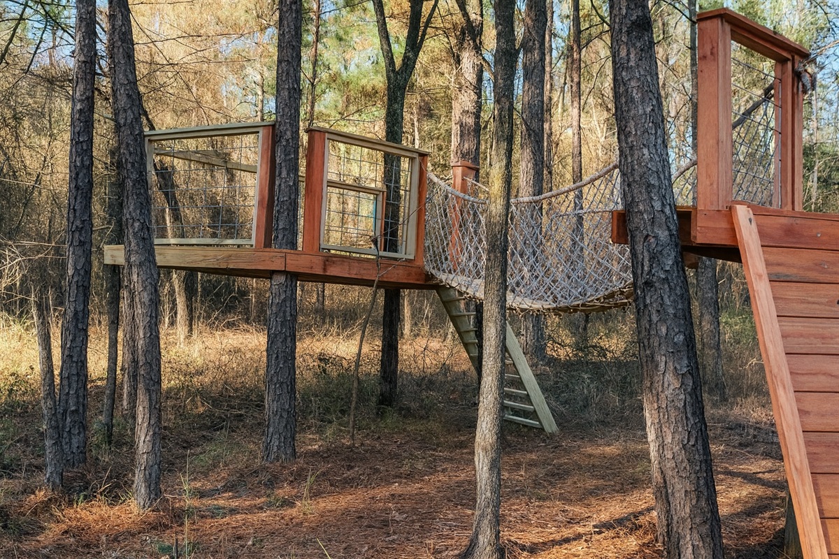 This custom treetop fort amnog the pines turns the backyard at Pinewood Lodge into a forest adventure they'll talk about long after the trip! 