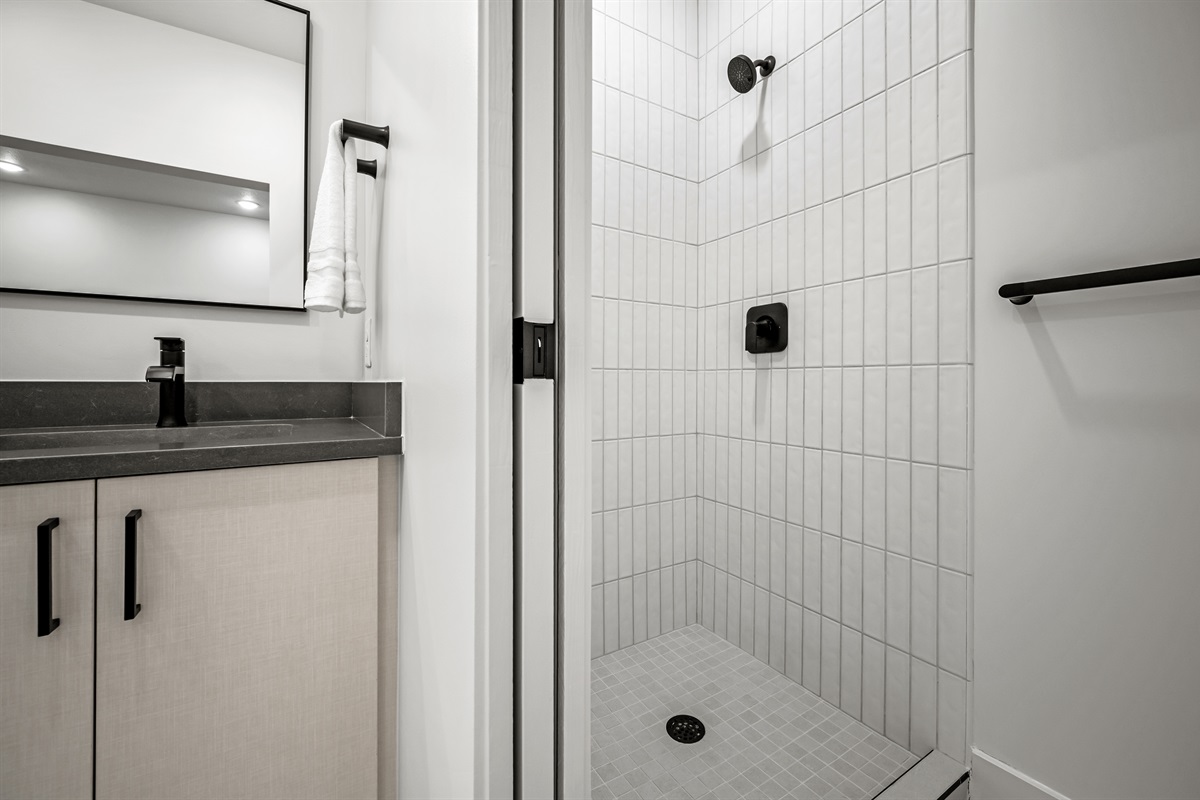 Step into the modern walk-in shower with elegant tile and matte black fixtures.