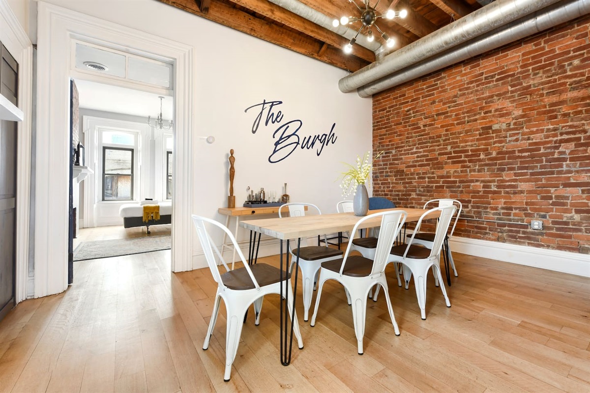 This huge dining space features a long table, six chairs, and an extra cushioned seat. Designed with simplicity and elegance, the room provides a warm and inviting atmosphere for meals, making every dining experience both stylish and comfortable.