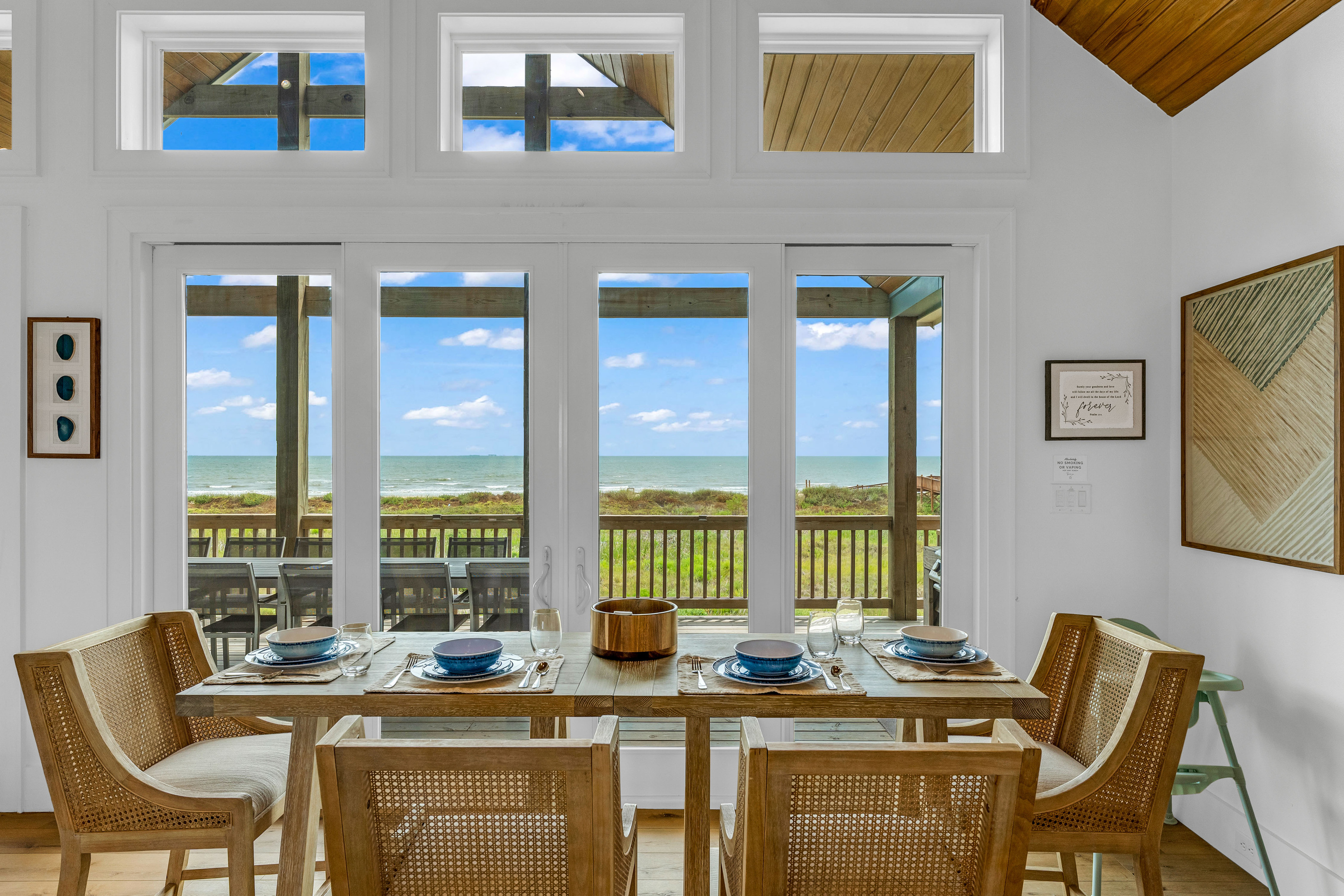 Cair Paravel: Woven cane chairs surround the dining table, set beneath a picture window framing an uninterrupted Gulf horizon, every meal comes with a view.