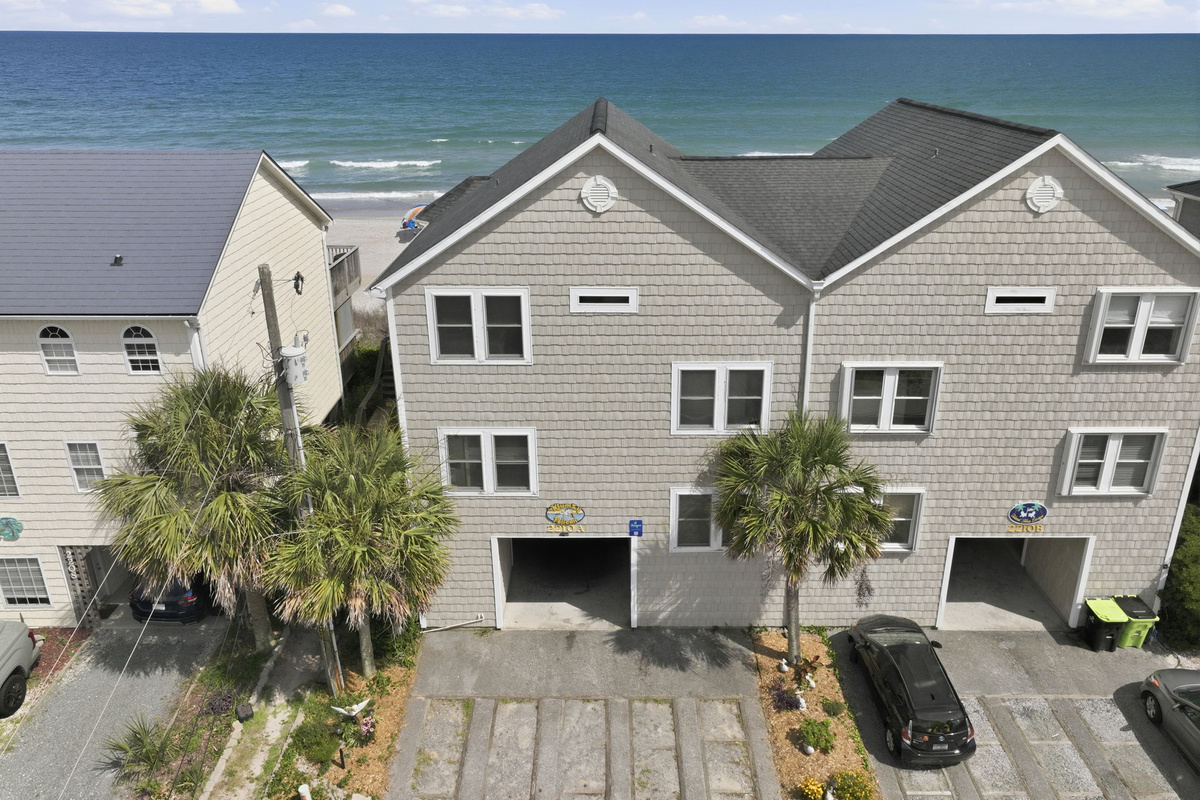 Klumzy Pelican exterior with covered parking and direct beach views from behind the property