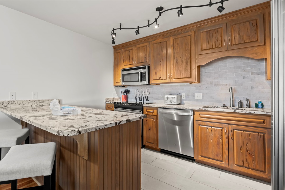 Prepare meals in the updated kitchen of our Cotton Bayou condo, featuring modern appliances, a stylish peninsula with extra seating, and a functional layout. Perfect for gathering and enjoying time with family and friends.