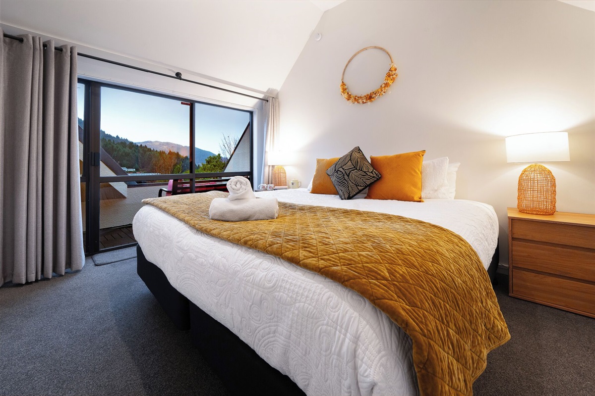 A super king bed, soft lighting and balcony access give this upstairs bedroom a comfortable base within the four-bedroom apartment.