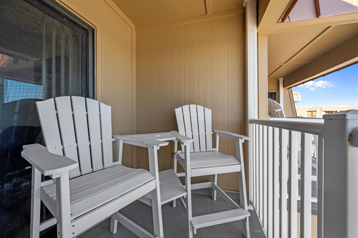 Covered balcony seating with a bistro table, perfect for coffee, cards, or ocean air breaks between adventures