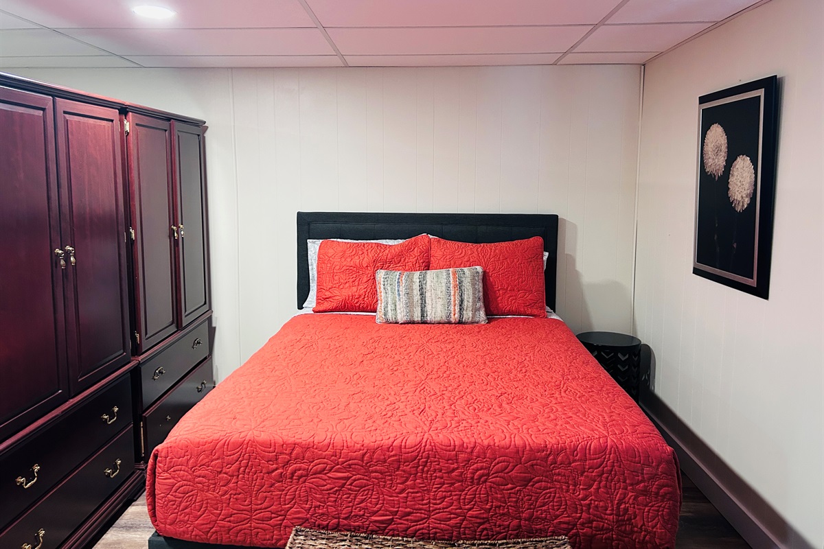 Queen bed in basement -- armoires separate the sleeping area of basement living room.