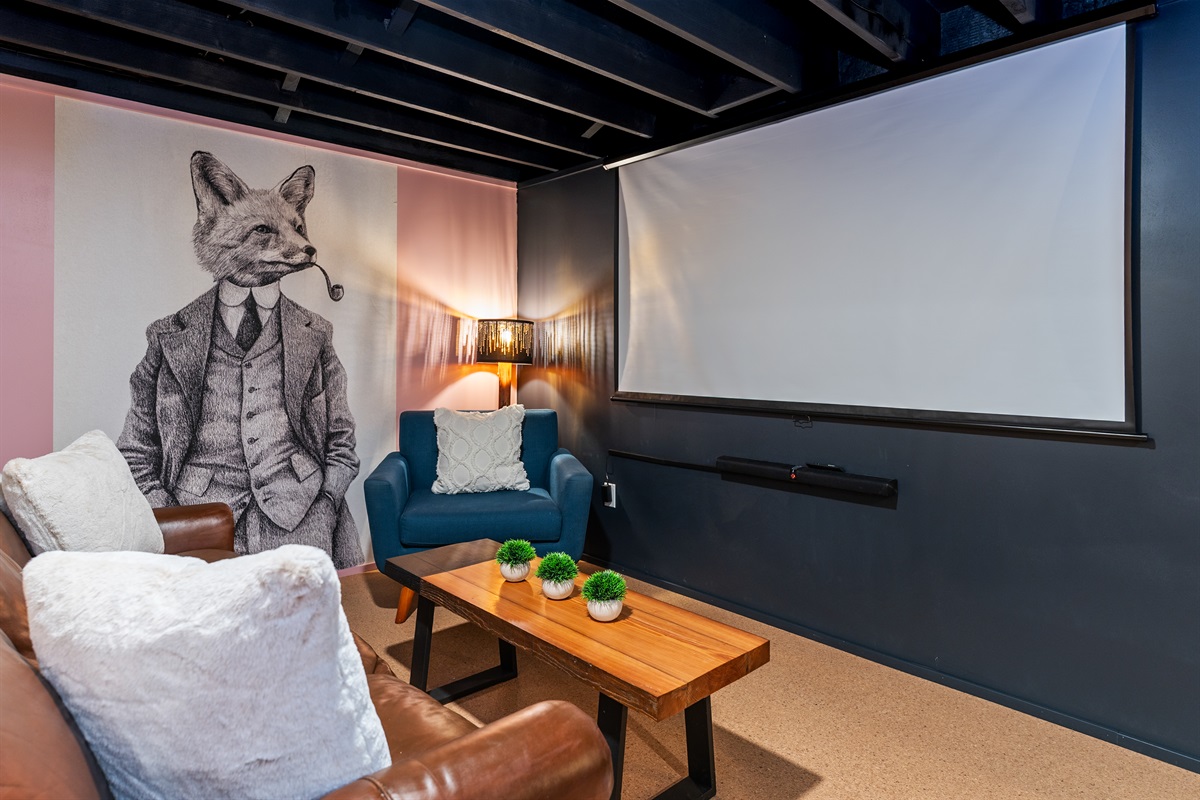 Cozy media lounge with sectional seating and a large projector screen for movie nights or sports viewing.